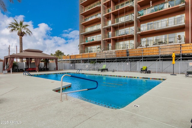 community pool with fence, a gazebo, and a patio