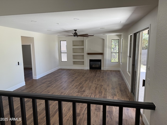 33220 N 60th Way, Scottsdale, AZ 85266 - unfurnished living room featuring built in shelves, dark wood-type flooring, a fireplace, and a ceiling fan