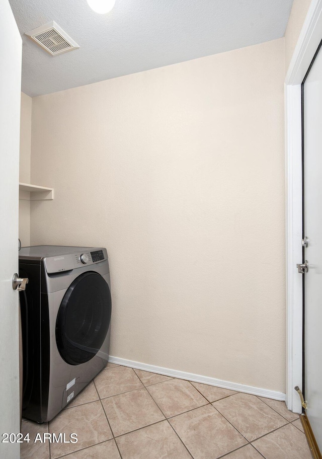 laundry area with washer / clothes dryer and light tile patterned flooring