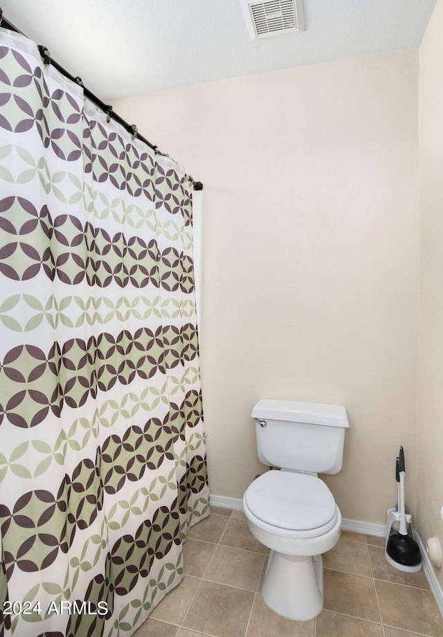 bathroom featuring a textured ceiling, toilet, and tile patterned floors