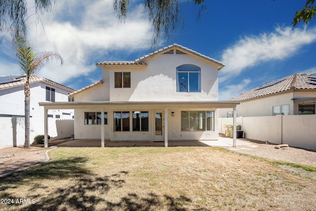 back of property with a lawn and a patio