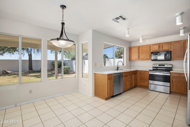 kitchen with pendant lighting, light tile patterned flooring, appliances with stainless steel finishes, and sink