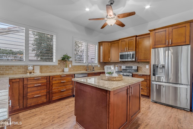 kitchen featuring appliances with stainless steel finishes, a healthy amount of sunlight, a center island, and light hardwood / wood-style flooring