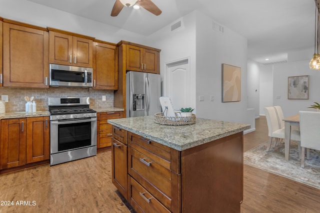 kitchen featuring tasteful backsplash, light hardwood / wood-style floors, appliances with stainless steel finishes, and a center island