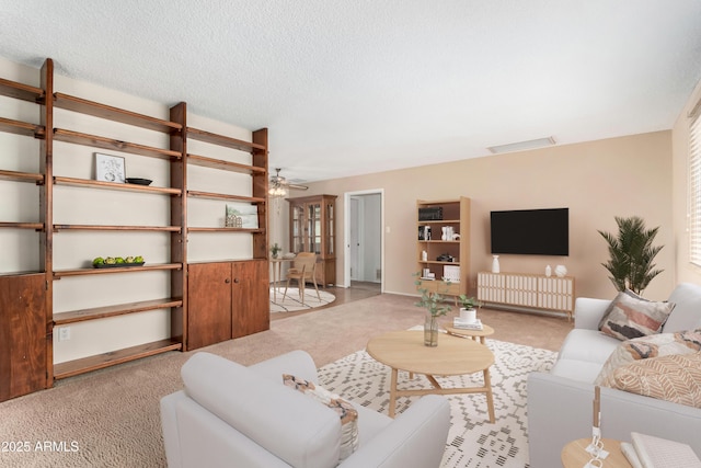 carpeted living room with ceiling fan and a textured ceiling