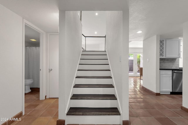 staircase featuring a textured ceiling and tile patterned floors