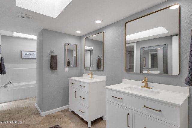 bathroom with tile patterned flooring, vanity, and tiled bath