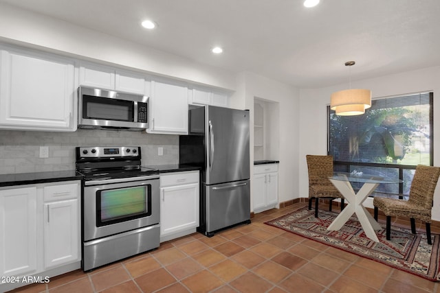 kitchen featuring white cabinetry, hanging light fixtures, backsplash, light tile patterned floors, and appliances with stainless steel finishes