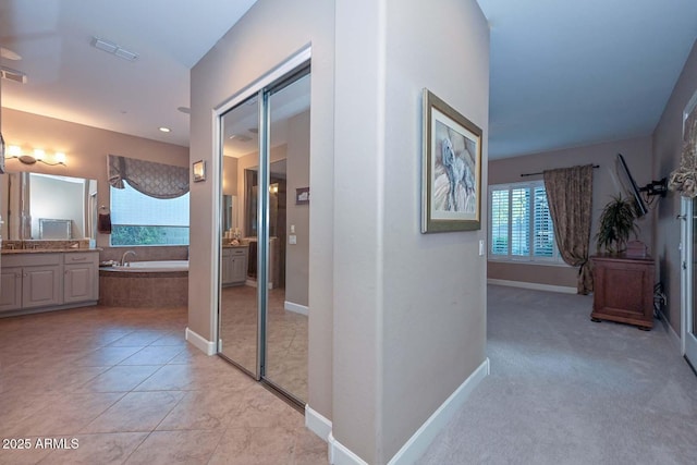 corridor featuring light tile patterned floors, visible vents, and baseboards