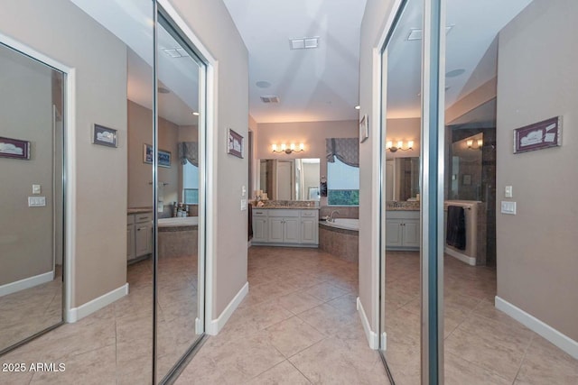 corridor with light tile patterned floors, baseboards, and visible vents