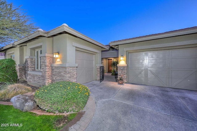 exterior space with a garage, stone siding, driveway, and stucco siding