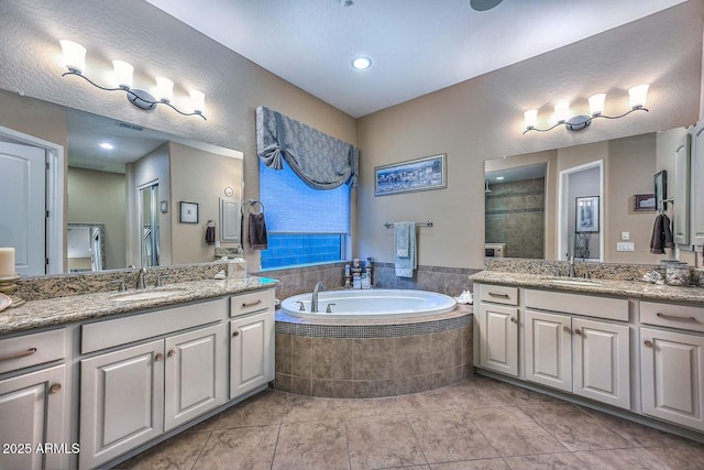 bathroom featuring a sink, a tile shower, two vanities, and a bath