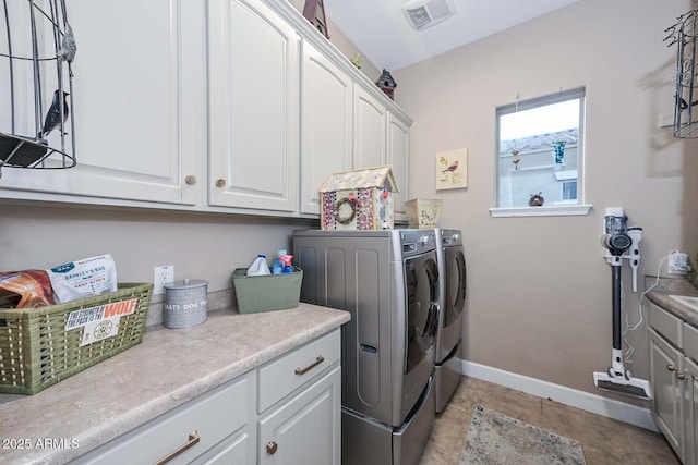 clothes washing area featuring light tile patterned floors, visible vents, baseboards, cabinet space, and washer and clothes dryer