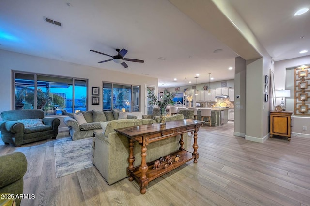 living area featuring baseboards, visible vents, a ceiling fan, light wood-type flooring, and recessed lighting