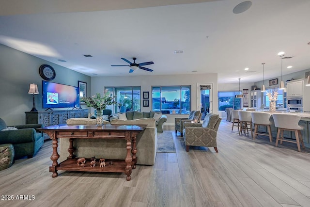 living room with light wood-type flooring, ceiling fan, visible vents, and recessed lighting