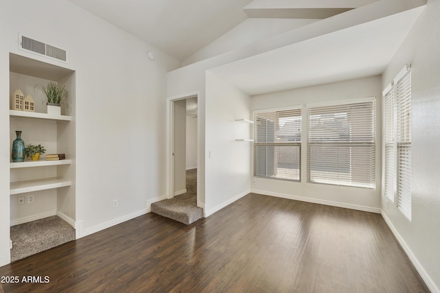 unfurnished room featuring built in shelves, dark hardwood / wood-style floors, a wealth of natural light, and vaulted ceiling