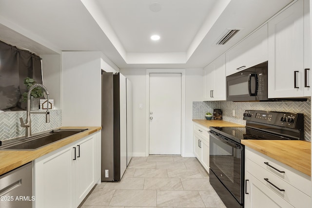 kitchen with white cabinets, sink, a tray ceiling, and black appliances