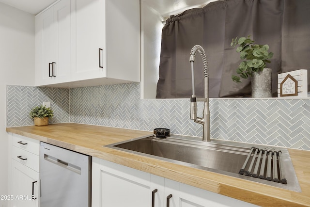 kitchen featuring wood counters, tasteful backsplash, sink, dishwasher, and white cabinetry