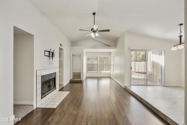 unfurnished living room featuring hardwood / wood-style flooring, ceiling fan, lofted ceiling, and a tiled fireplace