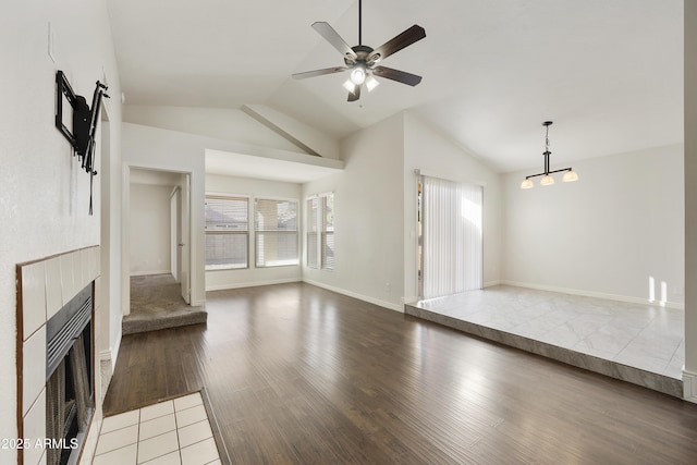 unfurnished living room featuring hardwood / wood-style floors, ceiling fan, a tiled fireplace, and vaulted ceiling