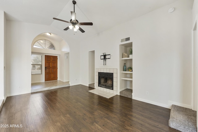 unfurnished living room with ceiling fan, dark hardwood / wood-style flooring, built in features, and a tile fireplace