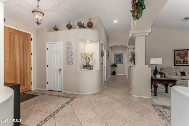 tiled entrance foyer with decorative columns and a notable chandelier