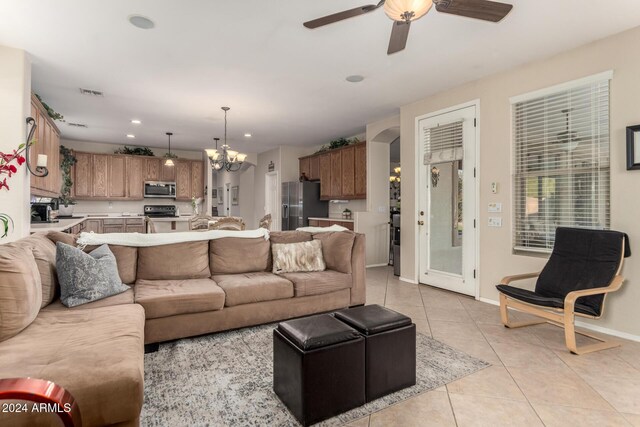 living room with light tile patterned floors and ceiling fan with notable chandelier