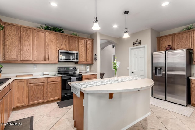 kitchen with a center island, a kitchen breakfast bar, light tile patterned floors, decorative light fixtures, and stainless steel appliances