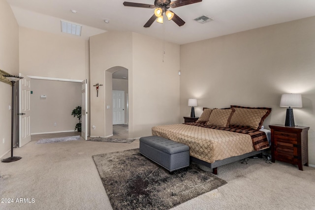 carpeted bedroom featuring ceiling fan and a high ceiling