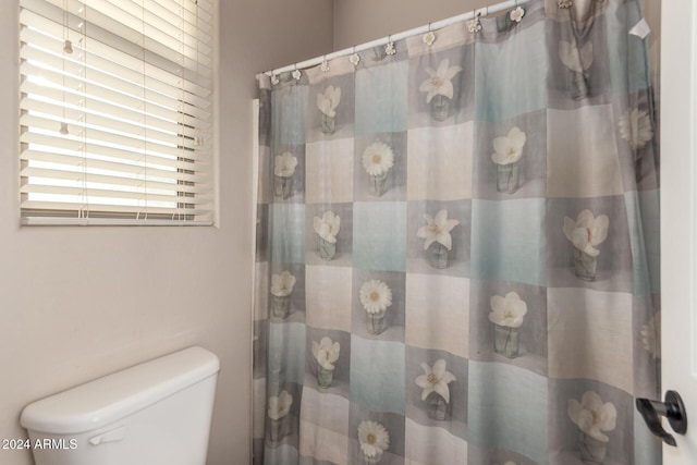 bathroom with a shower with shower curtain and toilet