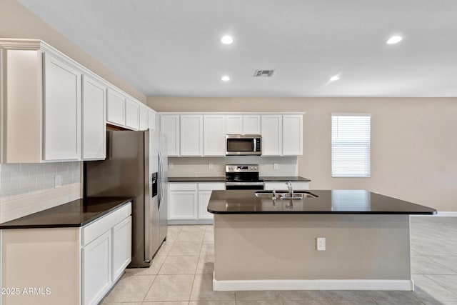 kitchen with light tile patterned floors, dark countertops, stainless steel appliances, white cabinetry, and a sink