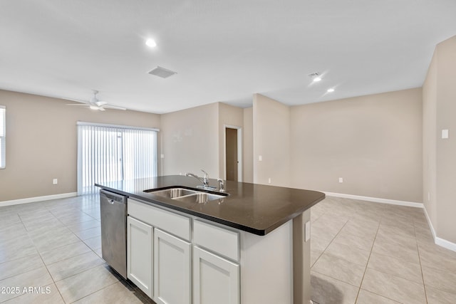 kitchen featuring dark countertops, light tile patterned flooring, dishwasher, and a sink