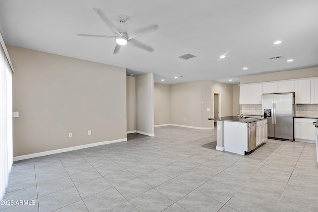 kitchen featuring stainless steel appliances, dark countertops, visible vents, decorative backsplash, and white cabinetry