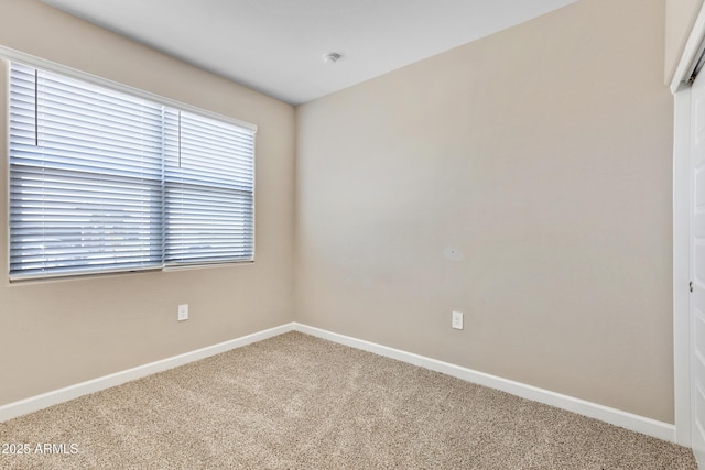 carpeted empty room featuring baseboards