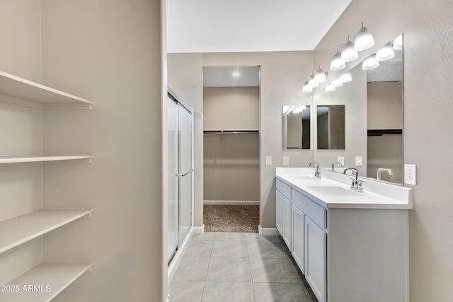 bathroom featuring a shower stall, double vanity, a sink, and tile patterned floors