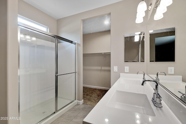 bathroom featuring double vanity, a stall shower, a sink, and tile patterned floors