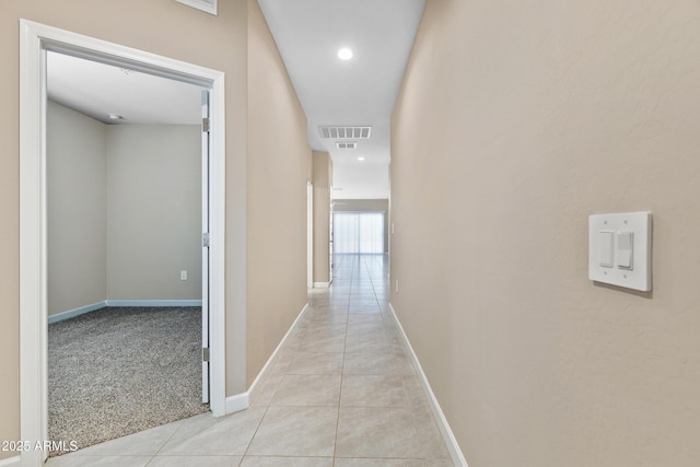 corridor with light carpet, light tile patterned floors, baseboards, and visible vents