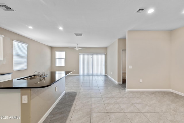 kitchen with light tile patterned floors, dark countertops, a sink, and visible vents