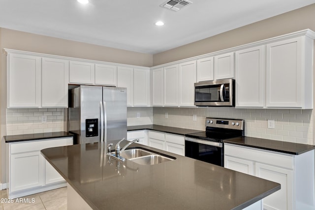 kitchen featuring visible vents, dark countertops, appliances with stainless steel finishes, a sink, and light tile patterned flooring