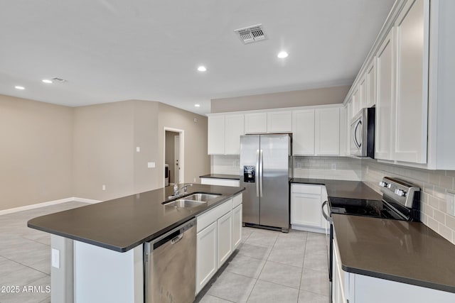 kitchen with appliances with stainless steel finishes, dark countertops, a sink, and light tile patterned floors