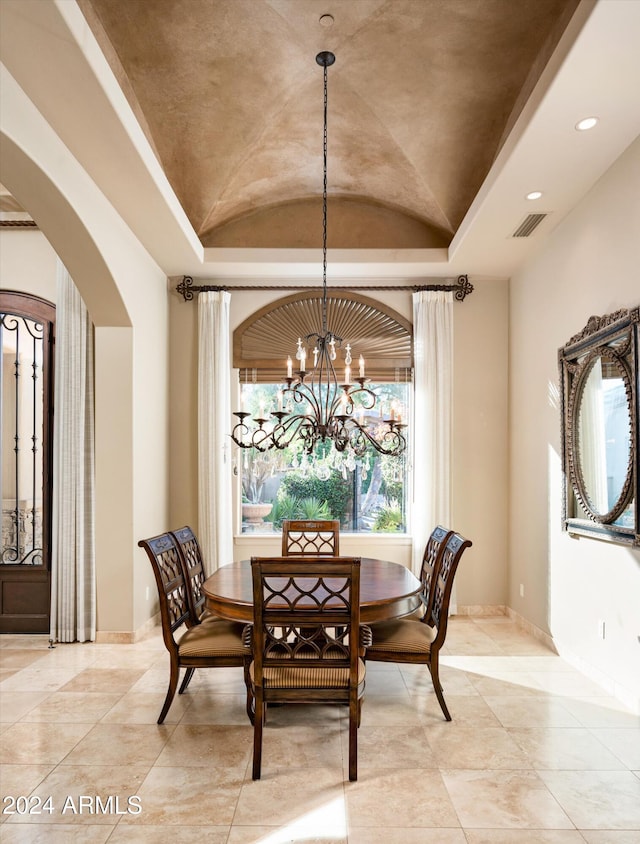 dining area featuring a chandelier, light tile patterned floors, and lofted ceiling