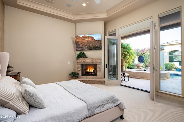 carpeted bedroom featuring access to outside and a tray ceiling