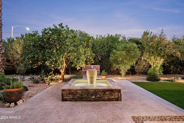 patio terrace at dusk featuring a yard