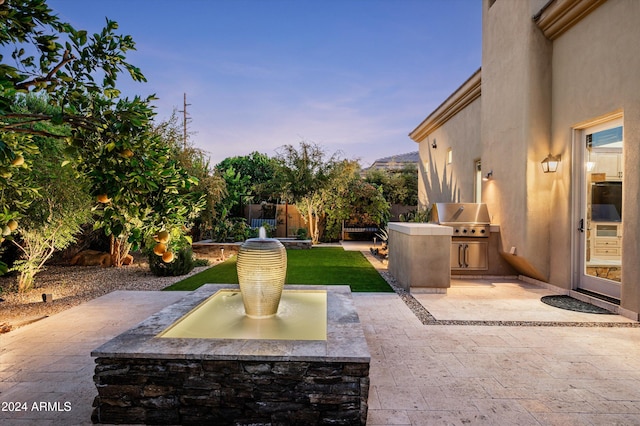 patio terrace at dusk featuring a grill and area for grilling