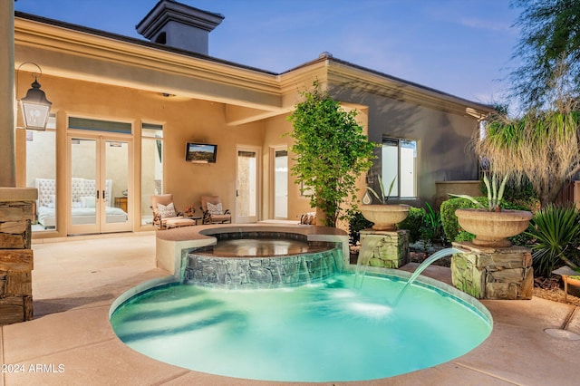 view of swimming pool with pool water feature, an in ground hot tub, and french doors