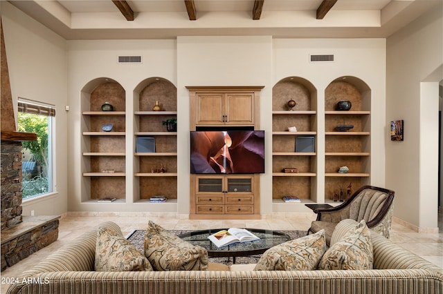 living room featuring a stone fireplace, built in features, and beamed ceiling