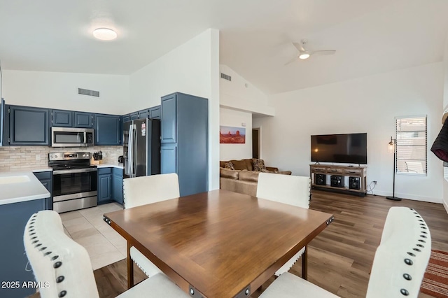 dining space featuring light wood-type flooring, high vaulted ceiling, visible vents, and a ceiling fan