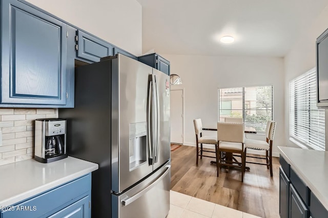 kitchen featuring light countertops, tasteful backsplash, blue cabinets, and stainless steel fridge with ice dispenser