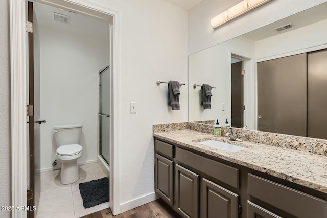 bathroom featuring visible vents, a stall shower, vanity, and toilet