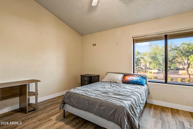 bedroom featuring a textured ceiling, vaulted ceiling, hardwood / wood-style flooring, and ceiling fan